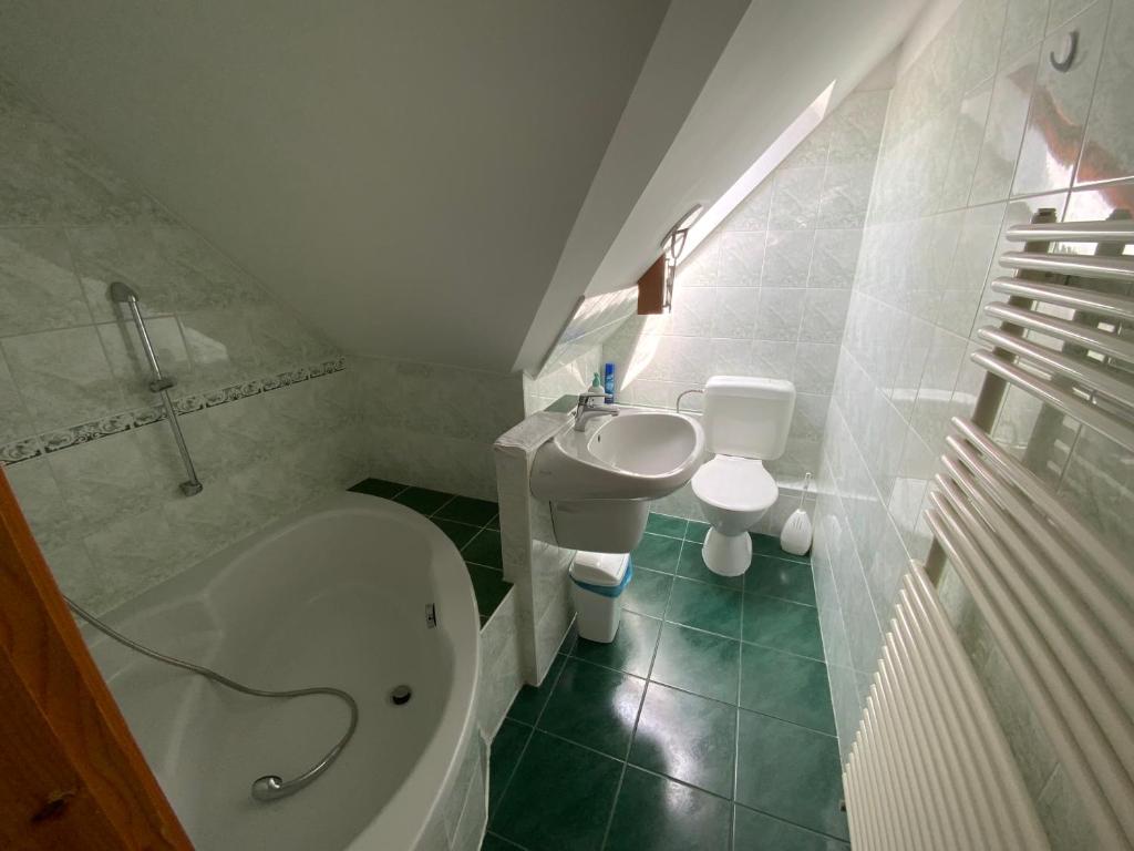 łazienka z umywalką, toaletą i wanną w obiekcie Gősy apartmanok w Siófoku
