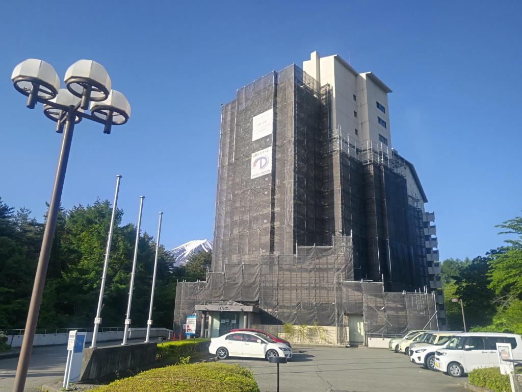 a tall building with cars parked in a parking lot at Hotel Regina Kawaguchiko in Fujikawaguchiko