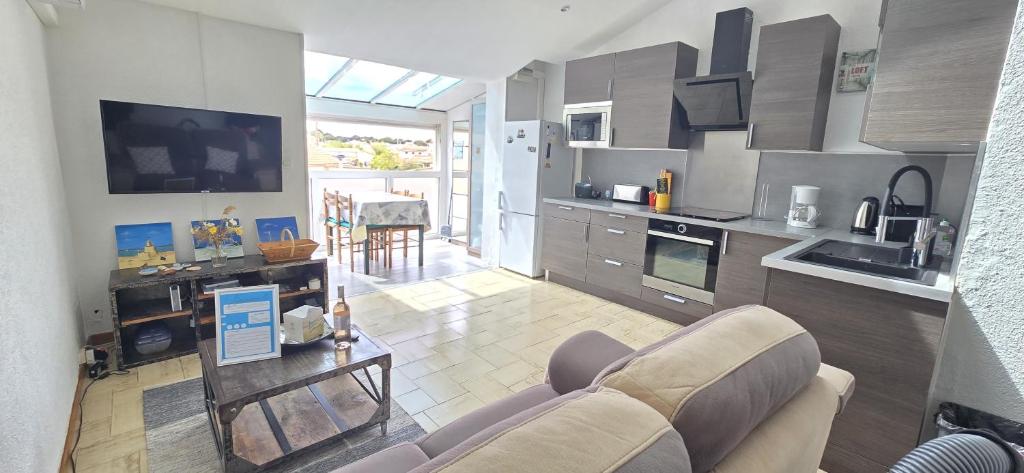 un salon avec un canapé et une cuisine dans l'établissement La lueur des marées - Appartement lumineux proche de la mer, à Sérignan
