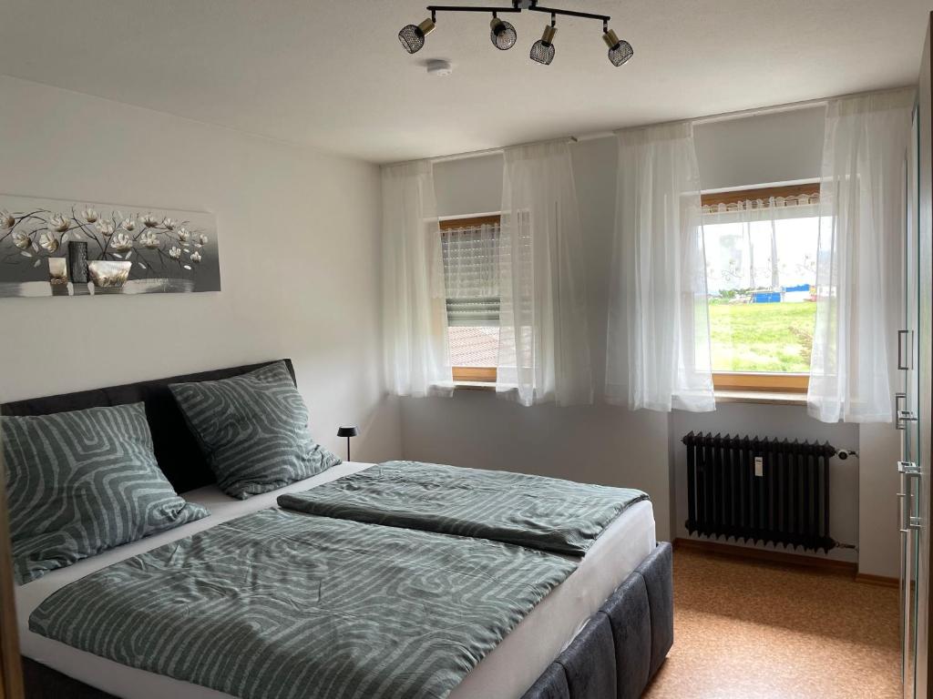 een slaapkamer met een bed en 2 ramen bij Ferienwohnung Alpenblick in Bruckmühl