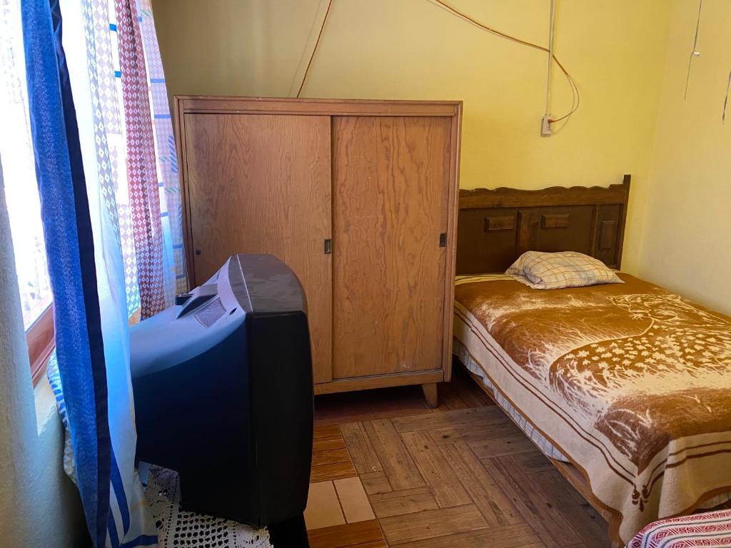 a small bedroom with a bed and a television at Granja ENCANES in Irapuato