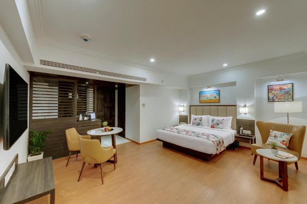ocaen Suites Near Delhi Airport في نيودلهي: غرفة فندقية بسرير وطاولة وكراسي
