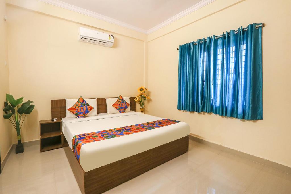 a bedroom with a bed and a blue curtain at FabExpress D Crescent in Shamshabad