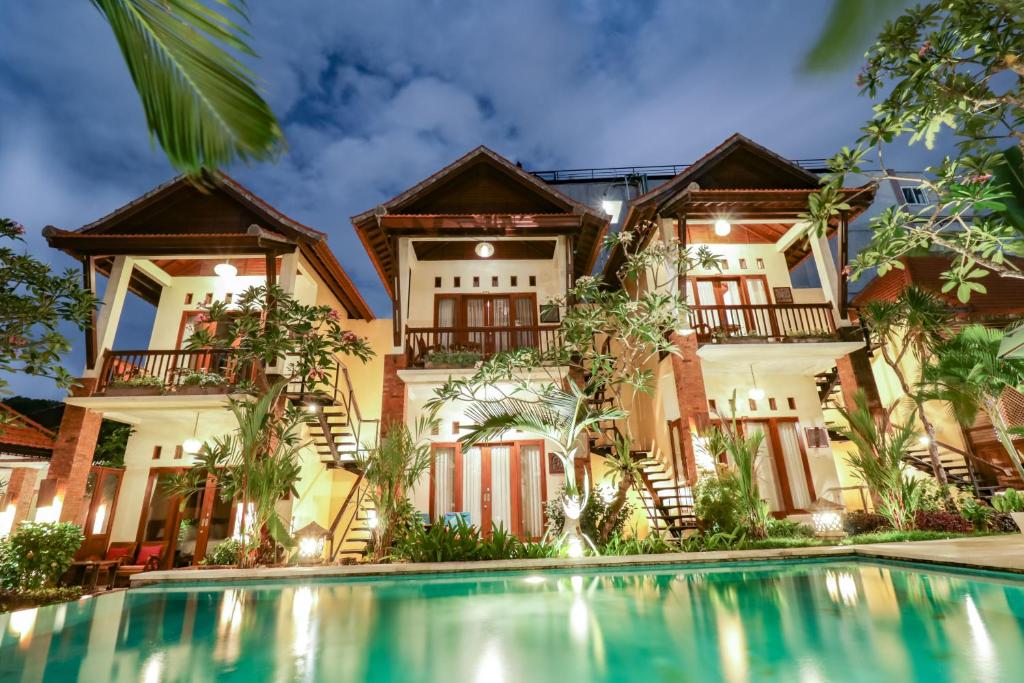 a house with a swimming pool in front of it at Mina Pelasa Hotel in Legian