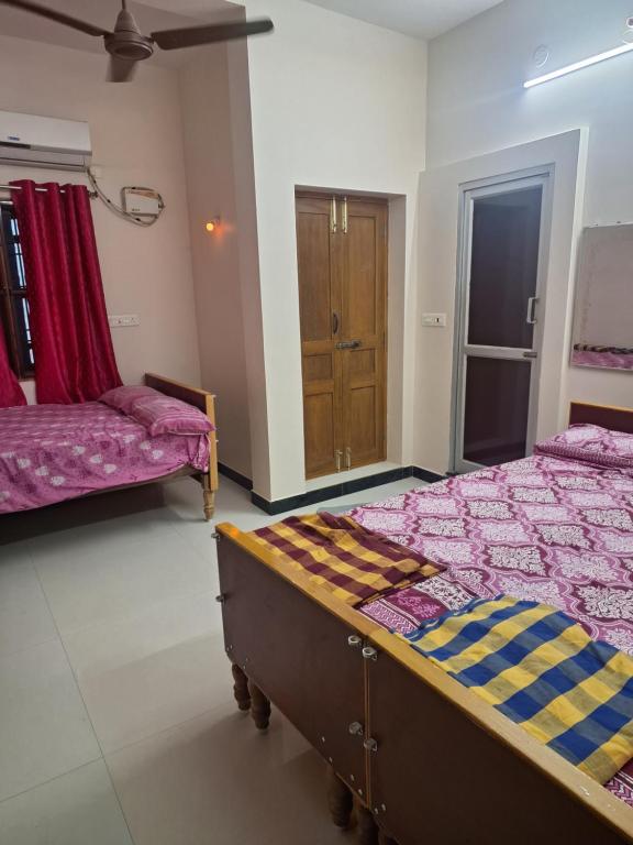 1 dormitorio con 2 camas y armario de madera en KG Homes, en Chidambaram