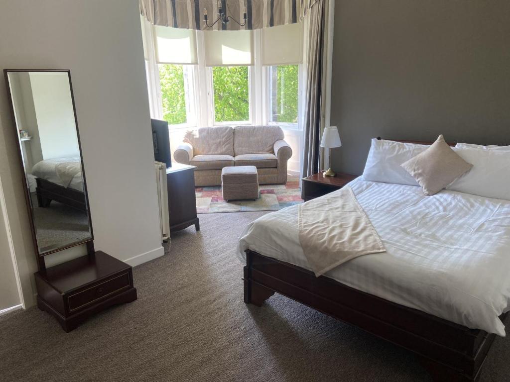 um quarto com uma cama, um espelho e um sofá em The Strathearn Hotel em Fife