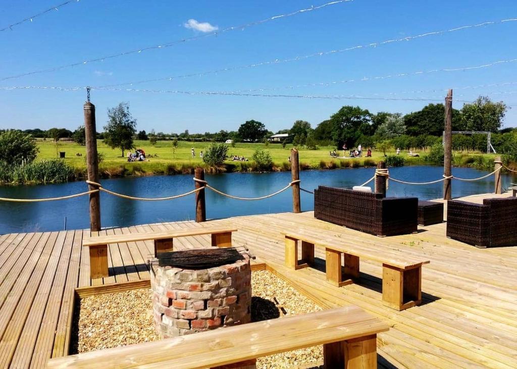 a wooden deck with a bench and a lake at Old Buckenham Country Park in Old Buckenham