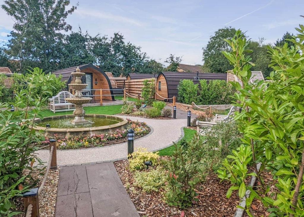 a garden with a fountain and a wooden house at Peacock Lake Glamping in East Bridgford