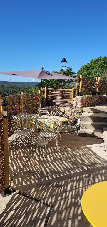 un patio avec tables, chaises et un parasol dans l'établissement Cigaloun, à Moissac-Bellevue