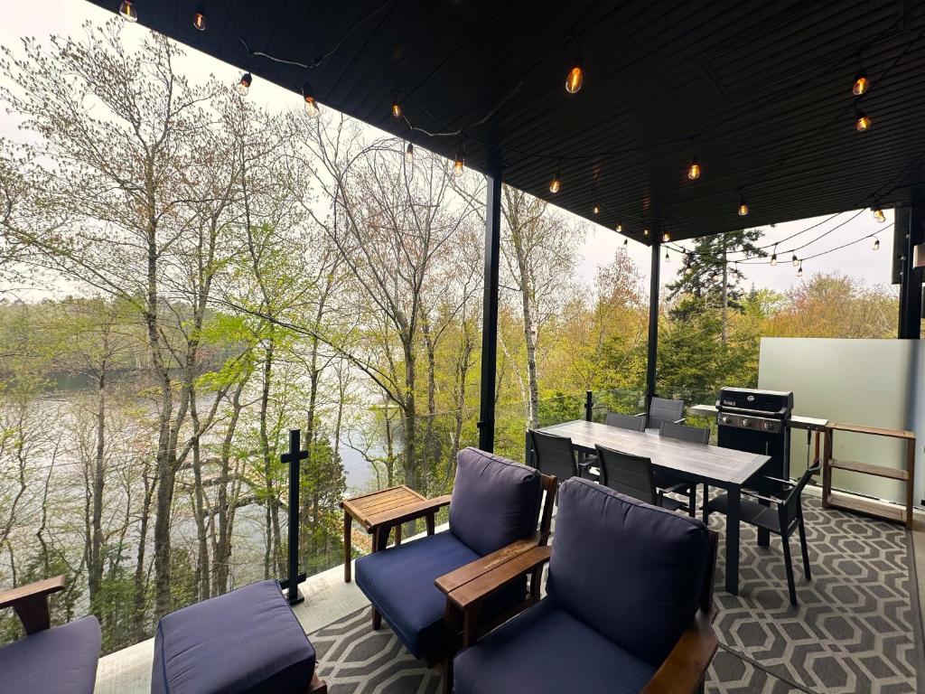 d'une terrasse couverte avec une table et des chaises offrant une vue sur la rivière. dans l'établissement Le Riverain - Condo neuf au bord de l'eau, à Shawinigan