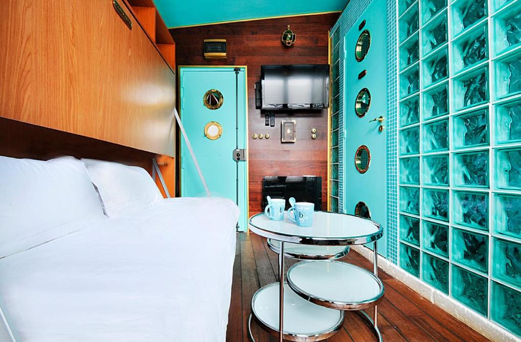 Cette petite chambre comprend un lit, une table et un lit. dans l'établissement Paris Marais Tiny Boat MERRIB, à Paris