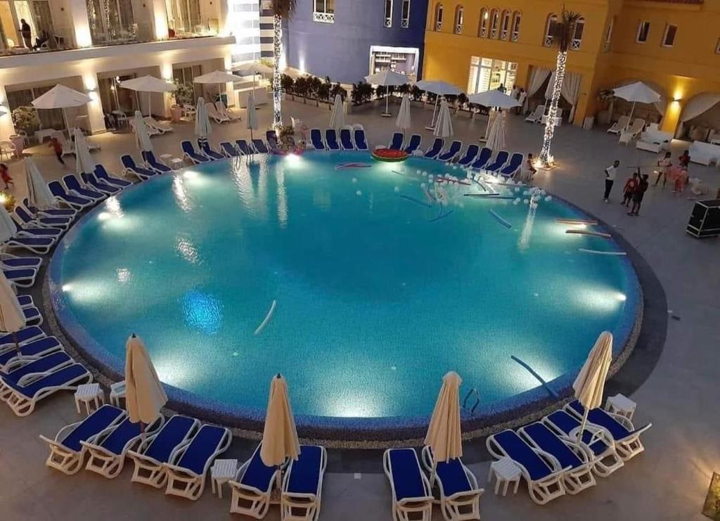 an overhead view of a large swimming pool with lounge chairs and a poologgle at premium sea porto marina suite in El Alamein