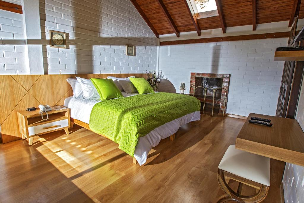 Schlafzimmer mit einem Bett mit grüner Bettwäsche und einem Schreibtisch in der Unterkunft Hosteria Totoral in Ibarra