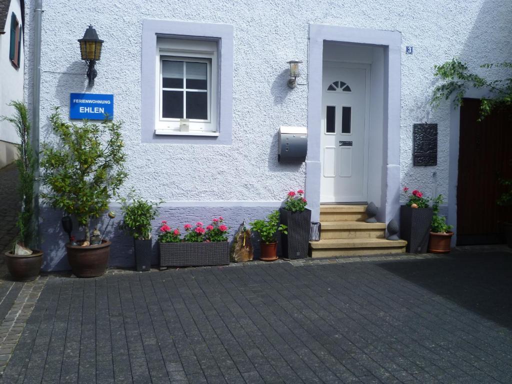 a white house with potted plants in front of it at Ferienwohnung Ehlen im Alten Winzerhaus in Zeltingen-Rachtig