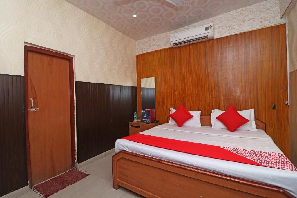 OYO 13234 Hotel Mahak في Bijnaur: غرفة نوم بسرير كبير ومخدات حمراء