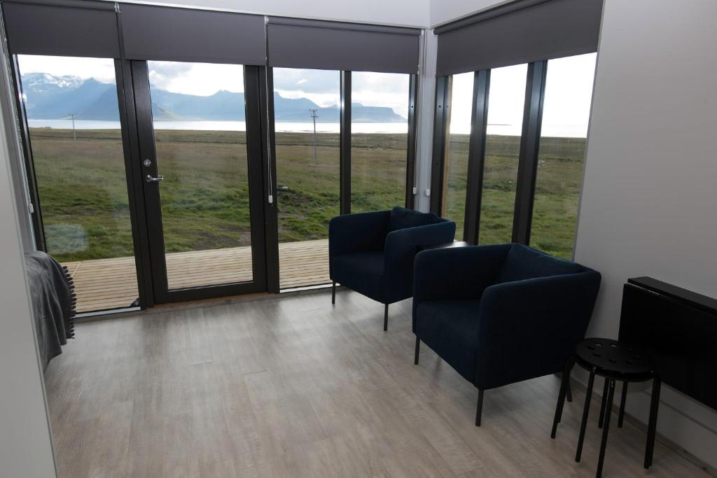 a room with two chairs and large windows at Dis Cottages in Grundarfjordur