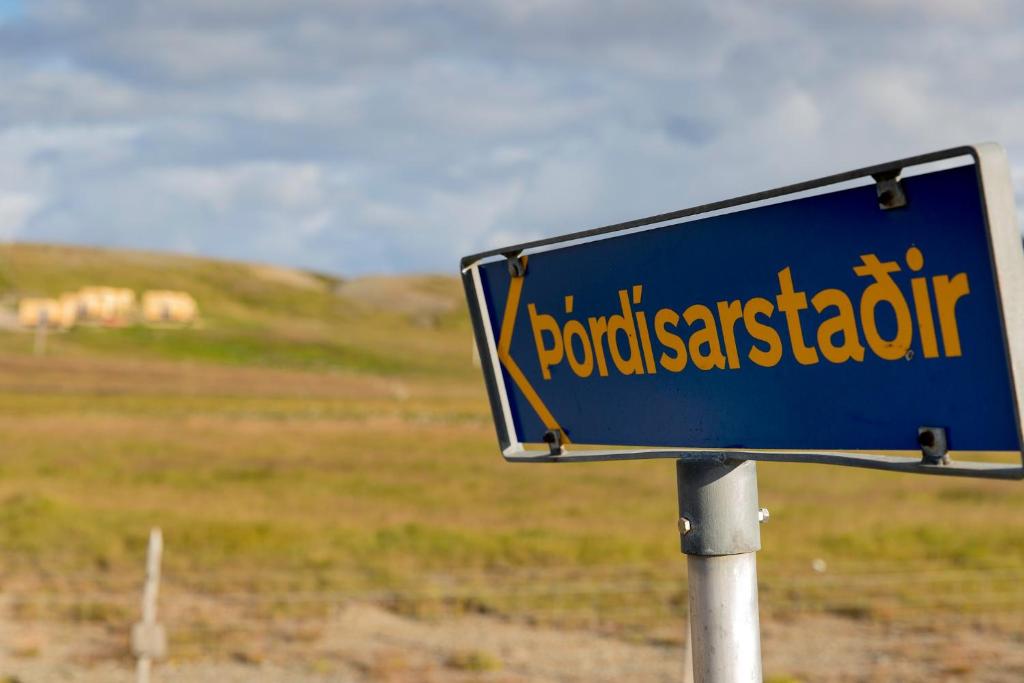 a blue street sign in front of a field at Dis Cottages in Grundarfjordur