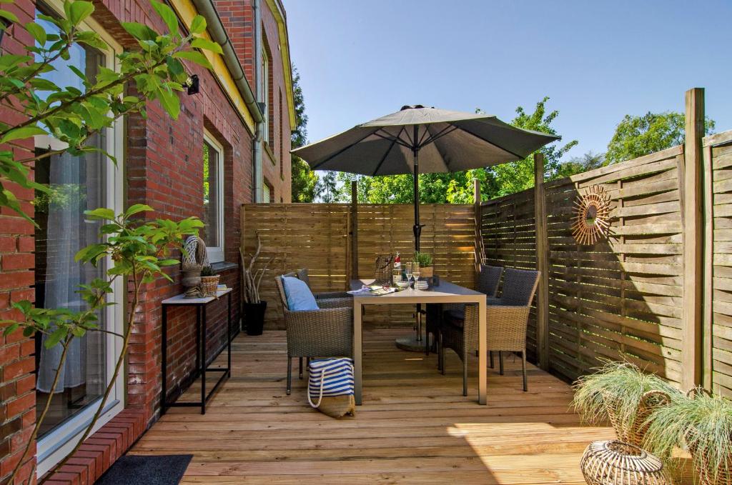 a wooden deck with a table and an umbrella at Ferienwohnung Fahrradland und Meer in Moormerland
