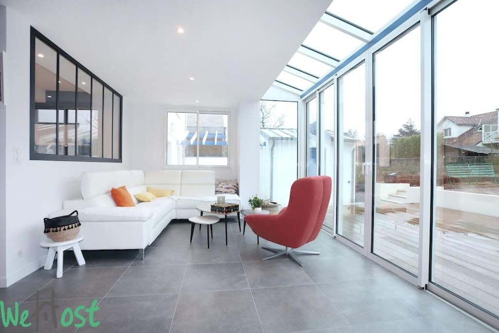 un salon avec un canapé blanc et une chaise rouge dans l'établissement PINCE [*Ty Bleuniou * ]- Proche mer et cœur de ville, à Pornichet
