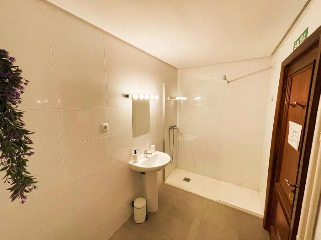 een witte badkamer met een wastafel en een douche bij Pensión las Hojas in Tudela
