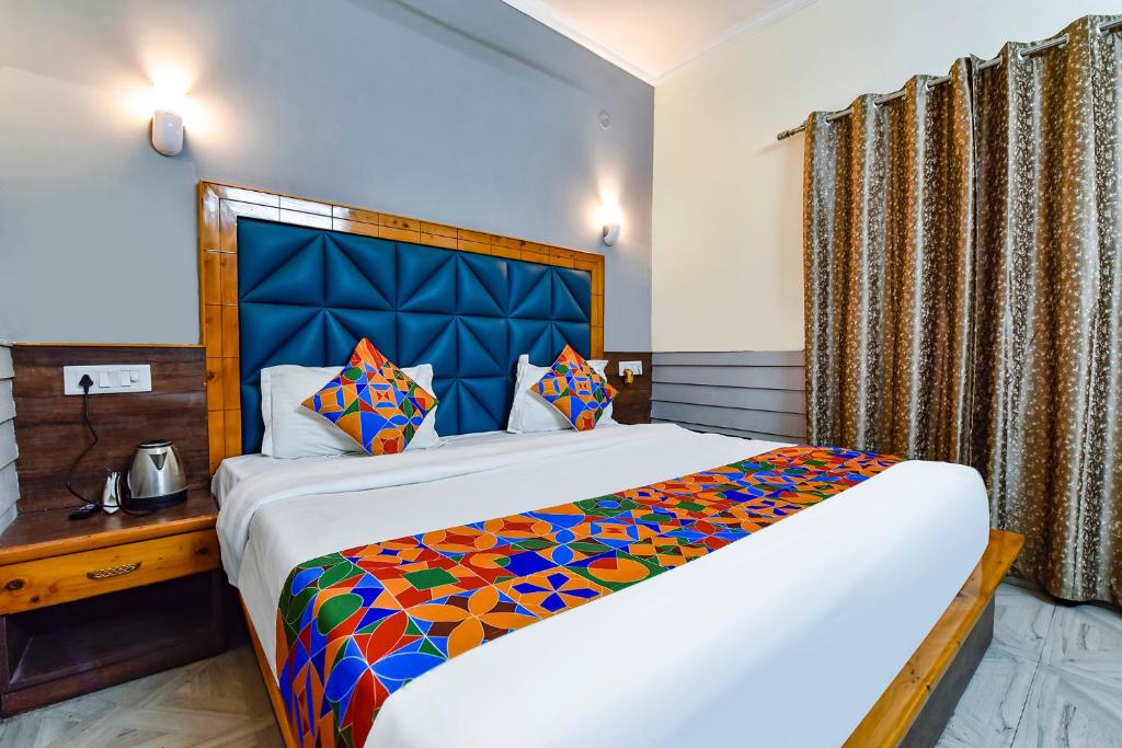a bedroom with a large bed with a blue headboard at FabHotel KK Residency in Mājra