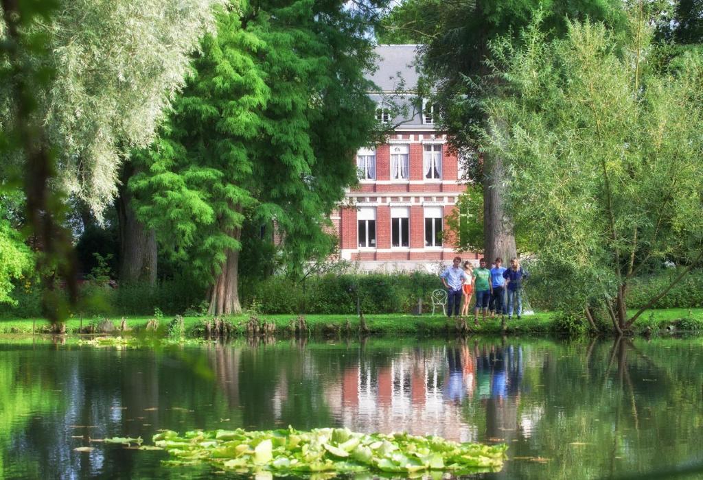 a group of people standing in front of a building next to a lake at Manoir de la Peylouse in Saint-Venant