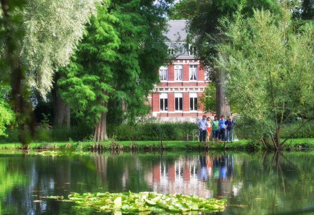 Saint-VenantにあるManoir de la Peylouseの湖畔の建物前に立つ人々