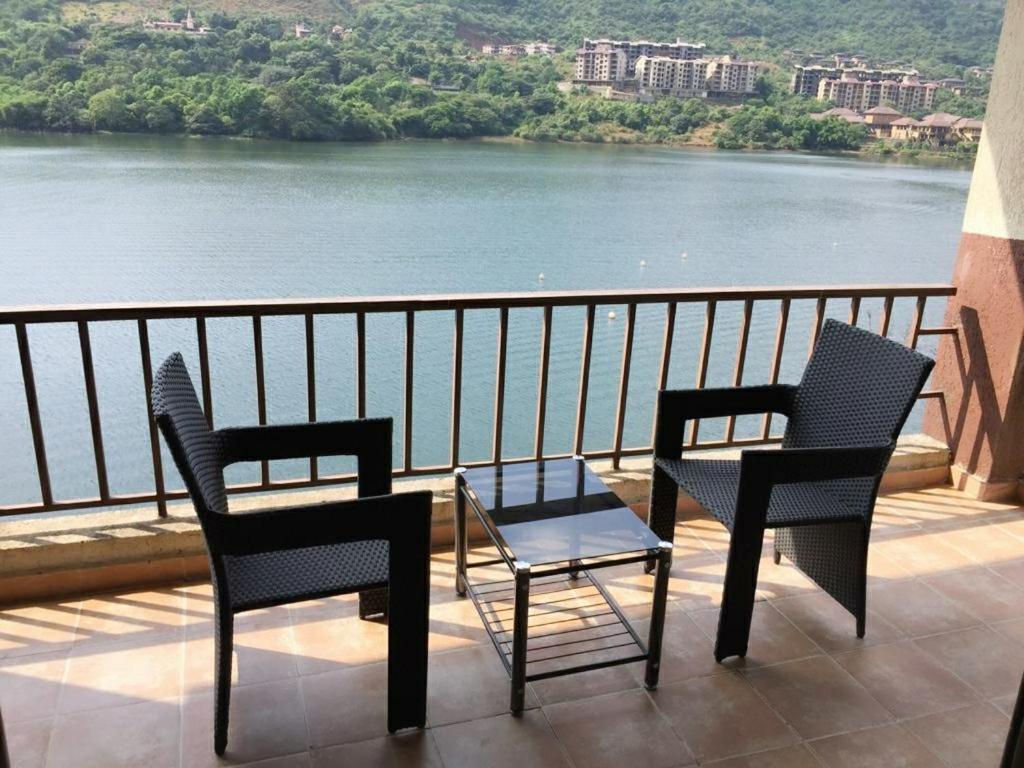 two chairs and a table on a balcony overlooking a river at Infinity Lake View Studio in Lavasa