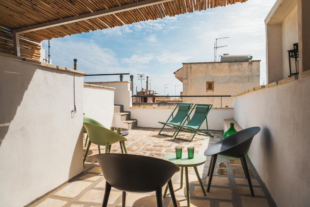 ein Balkon mit Stühlen und Tischen auf einem Dach in der Unterkunft Dimore Calculli - Puglia Mia Apartments in Monopoli
