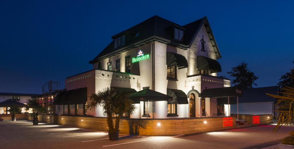 - un grand bâtiment blanc avec un panneau vert dans l'établissement Hotel-Restaurant Unicum Elzenhagen, à Poeldijk