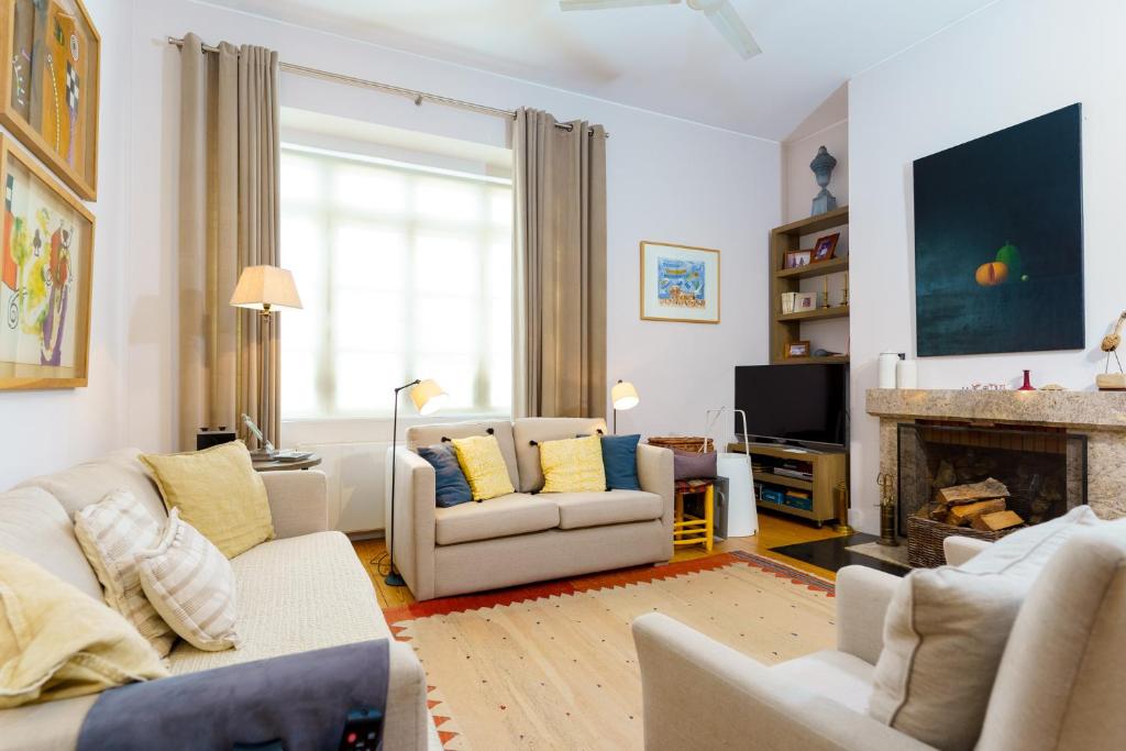 a living room with white furniture and a fireplace at Casa Cima Rio in Alcácer do Sal