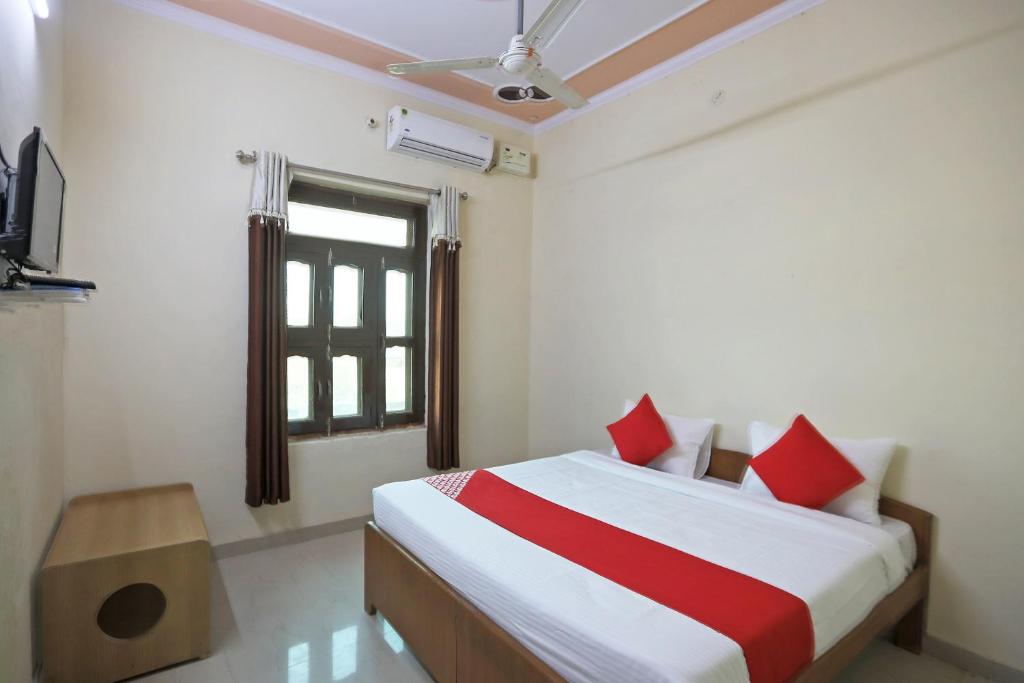 Un dormitorio con una cama con almohadas rojas y una ventana en OYO 62761 Hotel Daksh, en Mahendragarh