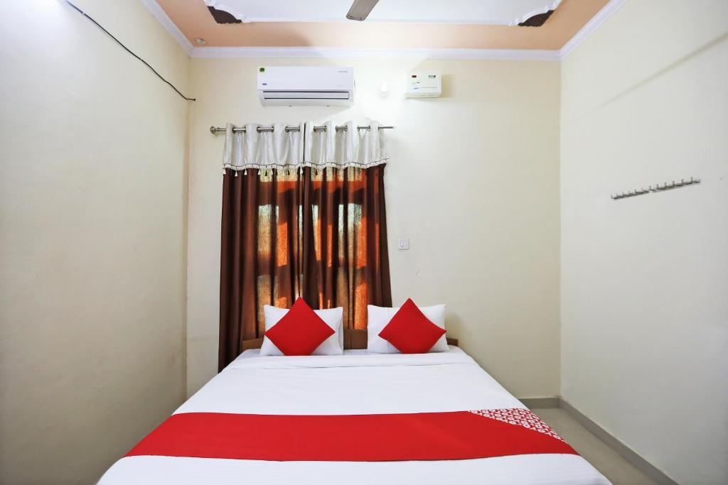 OYO 62761 Hotel Daksh في Mahendragarh: غرفة نوم بسرير ومخدات حمراء