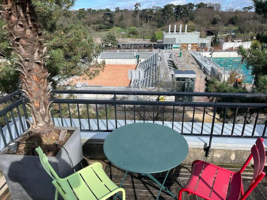 - un balcon avec une table et des chaises et un court de tennis dans l'établissement Special Olympics FlatTerrace Roland Garros View (145 m2 terrasse), à Boulogne-Billancourt