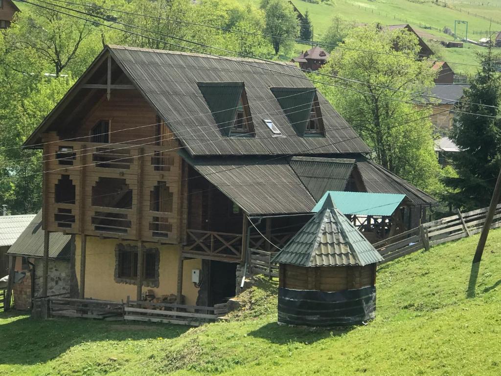 a house with a metal roof on a hill at Trembita готель in Yablunytsya