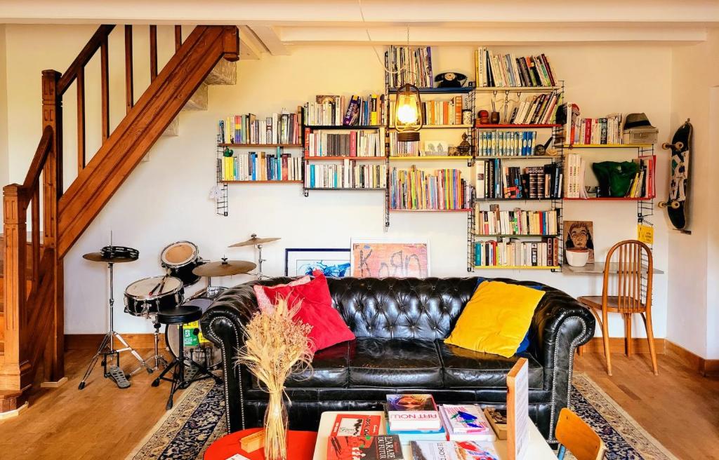 a living room with a leather couch and bookshelves at La Maison Folia in Contrières