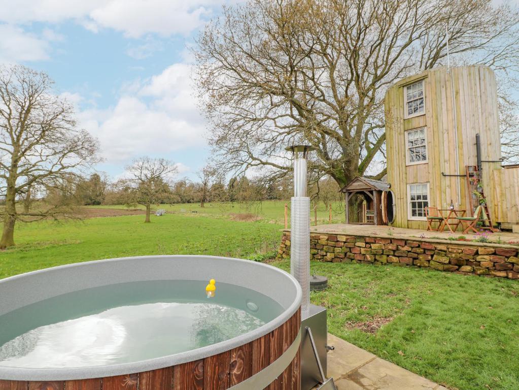 a jacuzzi tub in a yard with a building at The Lazy Squire by The Water in Rugeley
