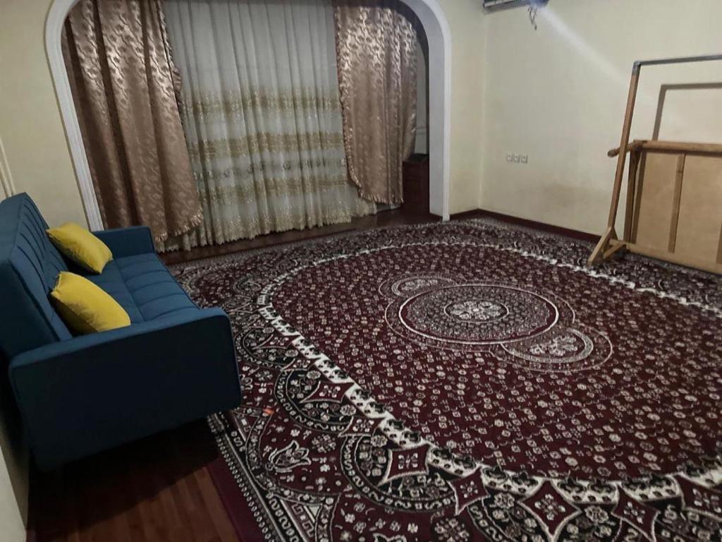ein Wohnzimmer mit einem blauen Sofa und einem Teppich in der Unterkunft Юнусабад 13 корзинка 