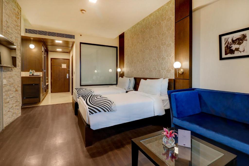 ein Hotelzimmer mit einem Bett und einem blauen Sofa in der Unterkunft Hotel Seven Villa Near Delhi Airport in Neu-Delhi