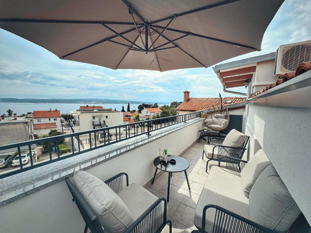 a balcony with chairs and an umbrella on a balcony at Knežević Apartments in Crikvenica