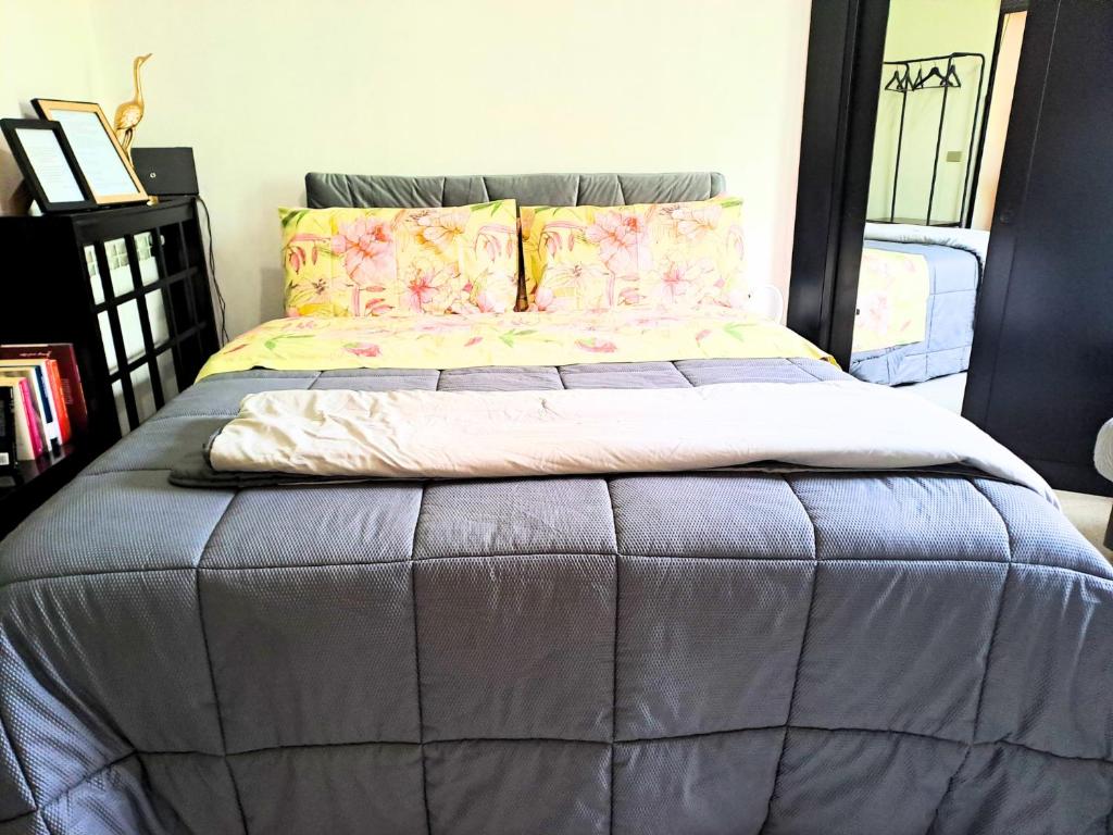 een groot bed in een slaapkamer met een grijs dekbed bij A due passi da Milano - Rho Fiera - Malpensa - Como in Saronno