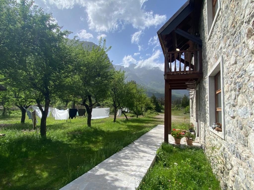 a path next to a building with trees in a field at Rupa Guest House in Theth