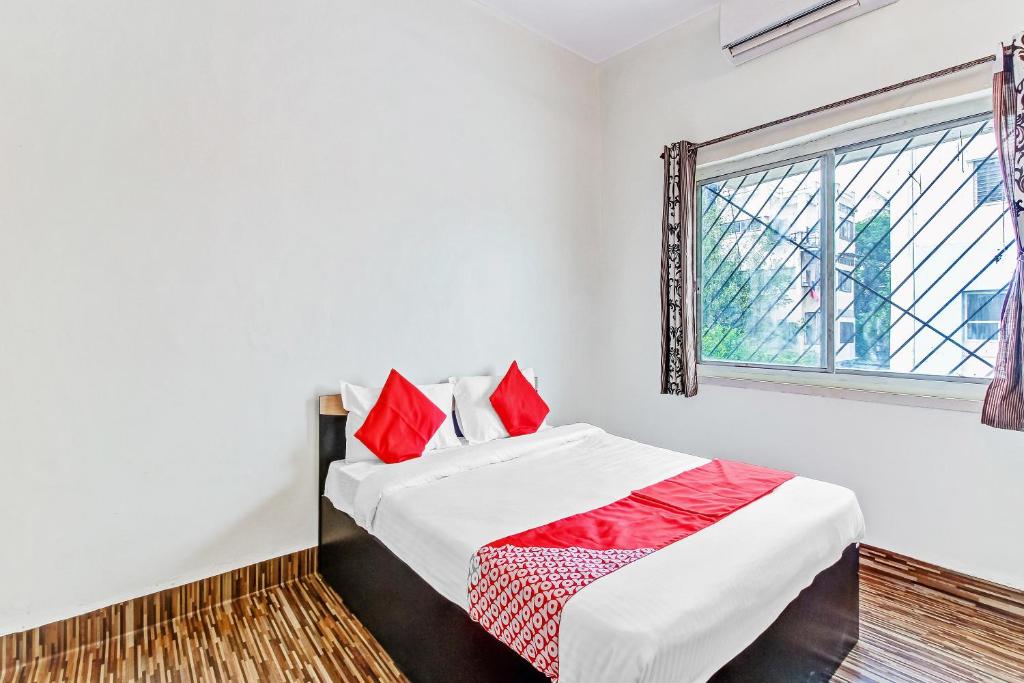 Un dormitorio con una cama con almohadas rojas y una ventana en OYO Shree Balaji Lodging, en Chikalthān
