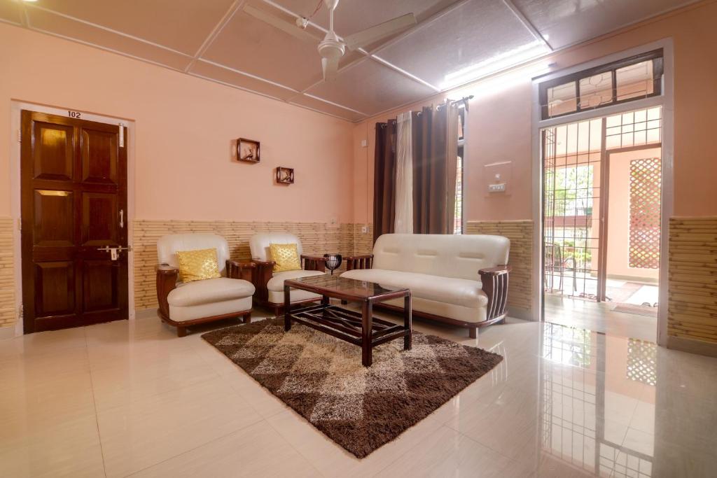 Collection O Trinayan Associates في ديبروجاره: غرفة معيشة مع كراسي وطاولة