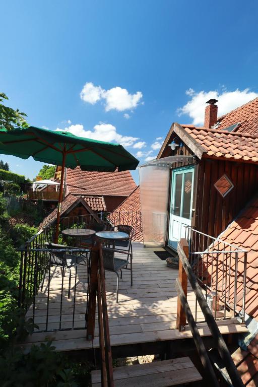 una terraza de madera con mesa y sombrilla verde en FeWo Kleinenbremen, en Porta Westfalica