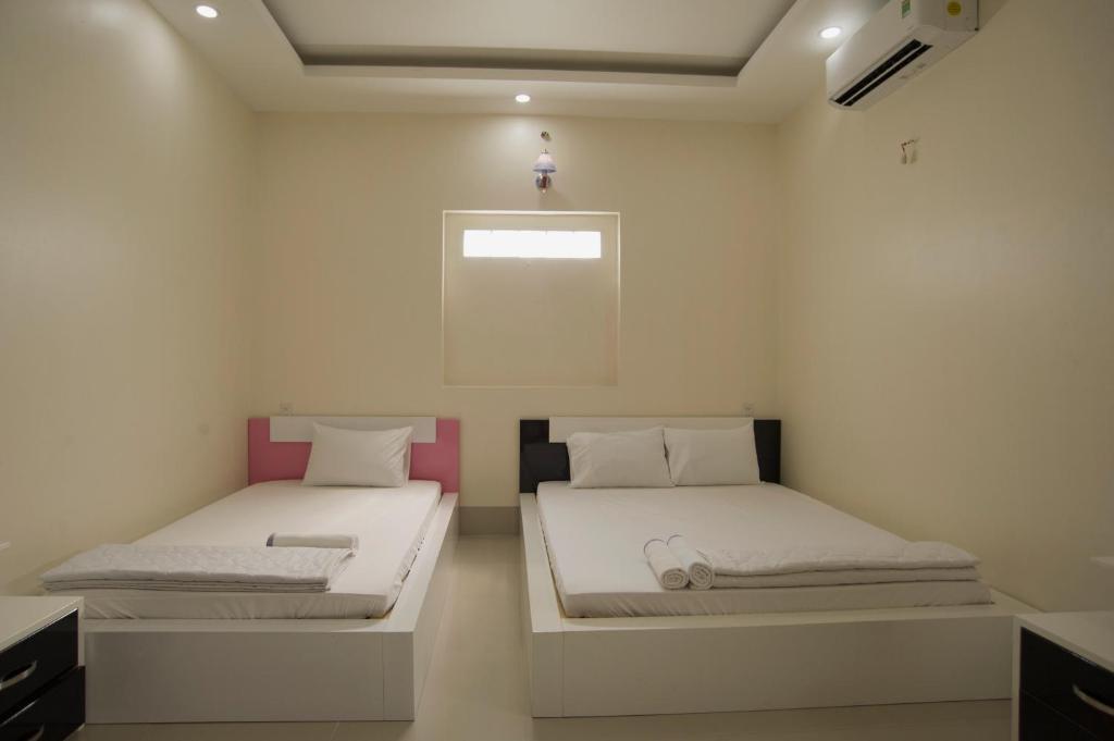 two beds in a room with white walls at Sao Mai An Giang Hotel in Ấp Mỹ Thạnh