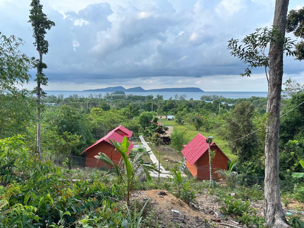 a group of red buildings in a field with trees at Maloop Cafe Bungalow in Koh Rong Island
