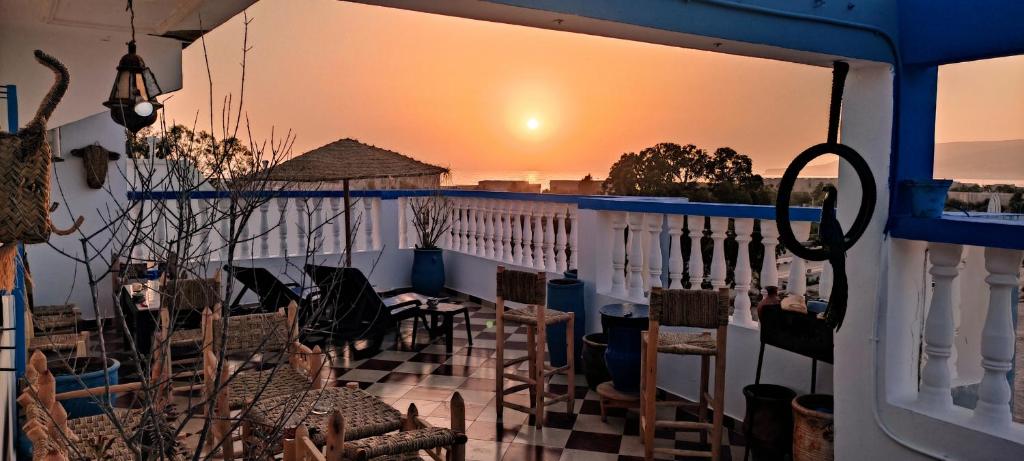 d'un balcon avec des chaises et un coucher de soleil en arrière-plan. dans l'établissement Free birds hostel, à Tamraght Ouzdar