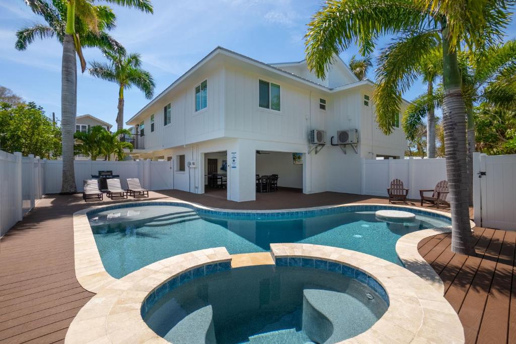una piscina frente a una casa con palmeras en Come relax in Paradise Found under the palms with private pool & spa, en Holmes Beach