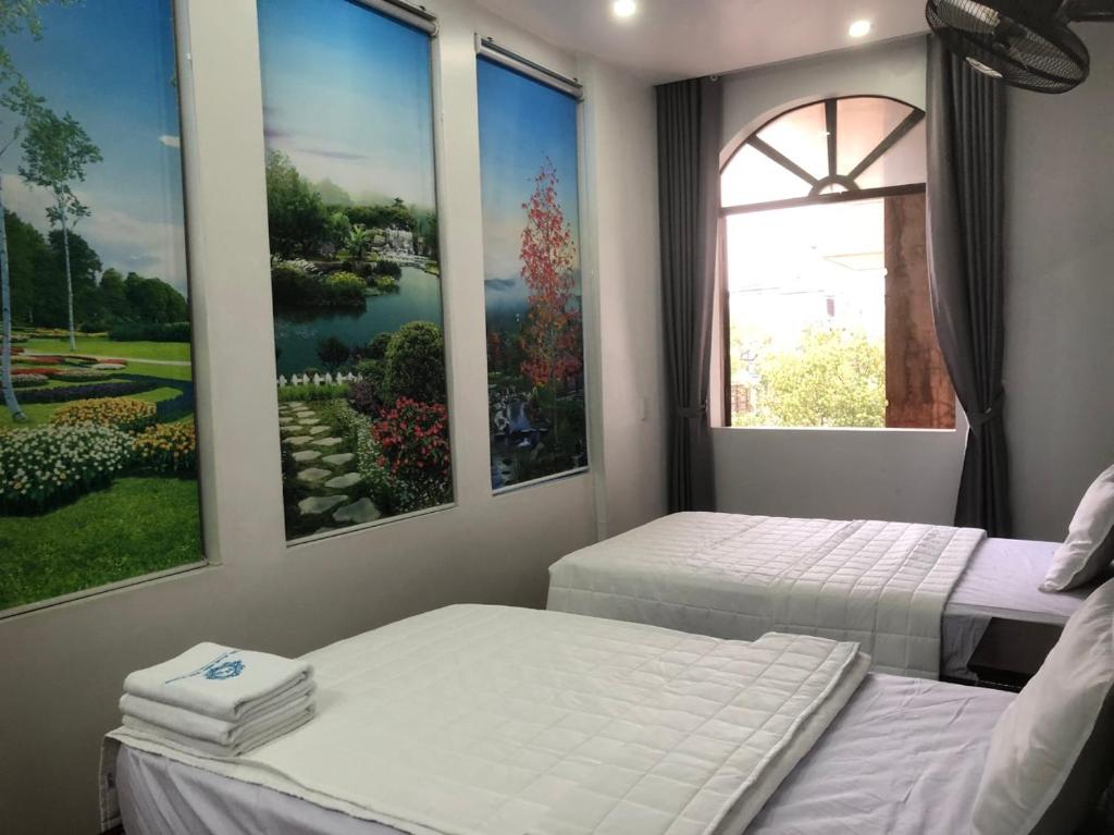 2 camas en una habitación con pinturas en la pared en Hotel Nam Sơn Tân Dương, en Hoàng Mai